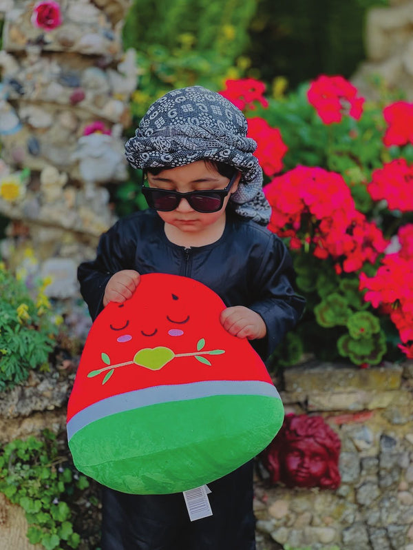 A young boy in a keffiyeh holding a large Nūr plushie