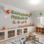 Green Ramadan Mubarak foil letters above a children's play area with a toy shelf and play rug
