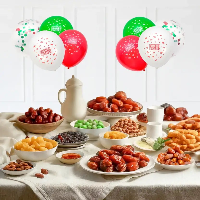 Bunches of red, green, white and confetti latex balloons floating above a table of dates and snacks