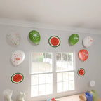 Ramadan Mubarak latex balloons and watermelon paper fans stuck to a wall beside two windows