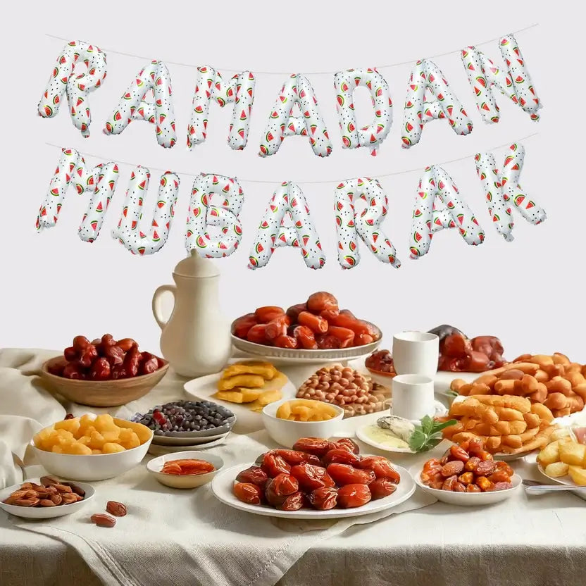 White watermelon-print Ramadan Mubarak foil balloons hung above a table of dates and snacks