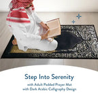 Man in a red-and-white checked headdress reading a book on the Dark Arabic Calligraphy padded prayer mat