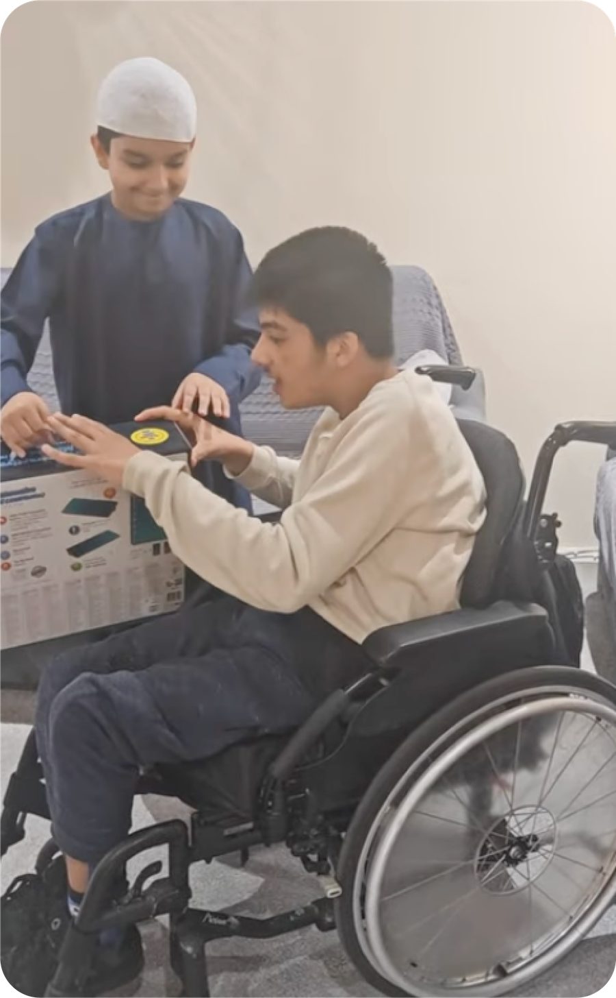 A young man in a wheelchair using the interactive prayer mat with Eisa