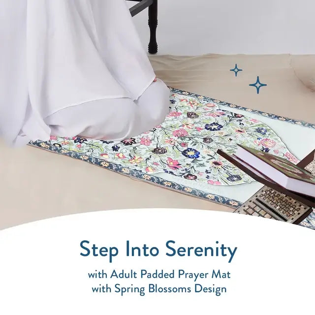 Person in white kneeling on the Spring Blossoms padded prayer mat with a Quran on a stand beside it
