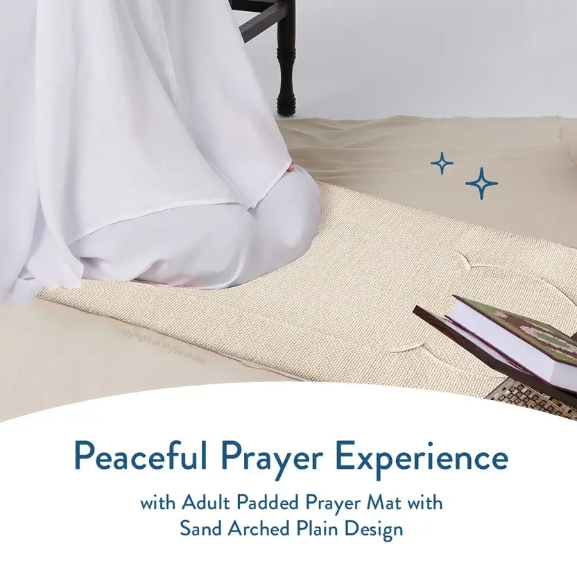 Person in white prayer clothes kneeling on the Luxury Sand Arched padded mat beside a Quran stand